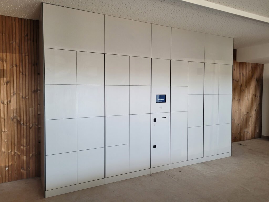 Casier connecté intelligent installé en intérieur dans le hall d'une entreprise. Fabriqué à partir de bois stratifié coloris blanc nacré.