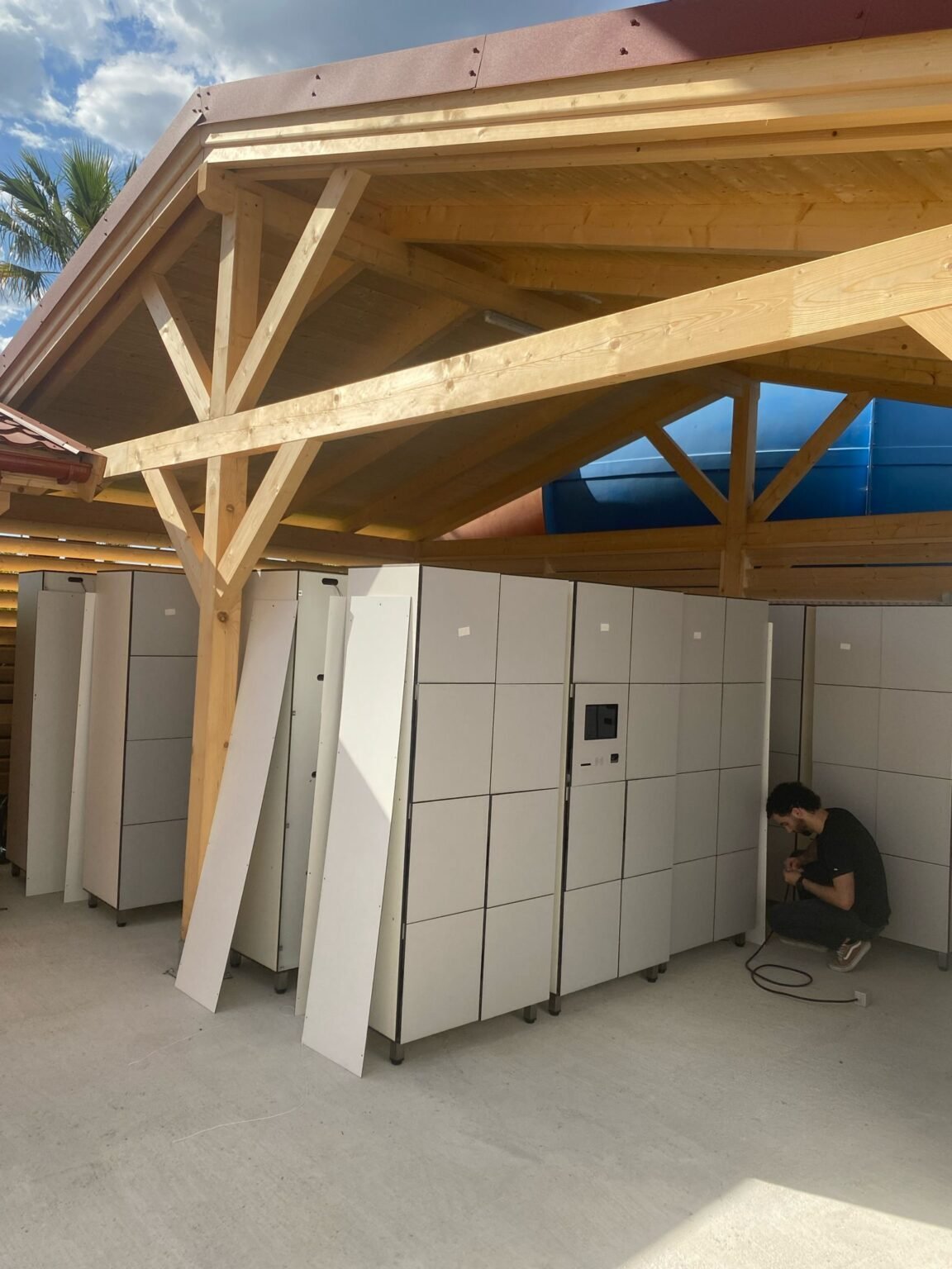 Casiers connectés blancs installés sous un abri en bois, intégration aux systèmes ERP pour optimiser la gestion des ressources en entreprise