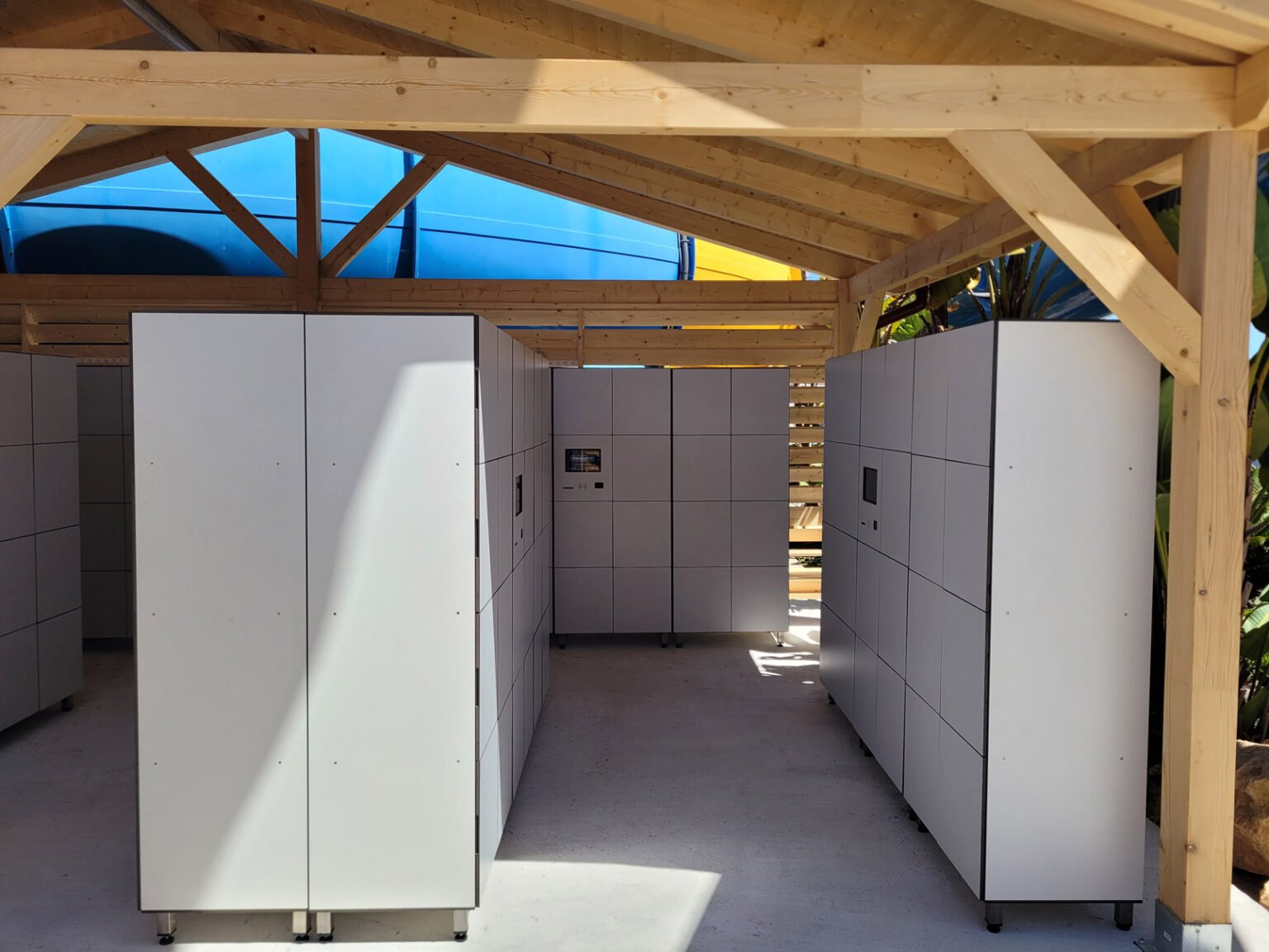 Casiers connectés blancs sous une structure en bois, offrant un espace de travail flexible et sécurisé pour le bureau moderne