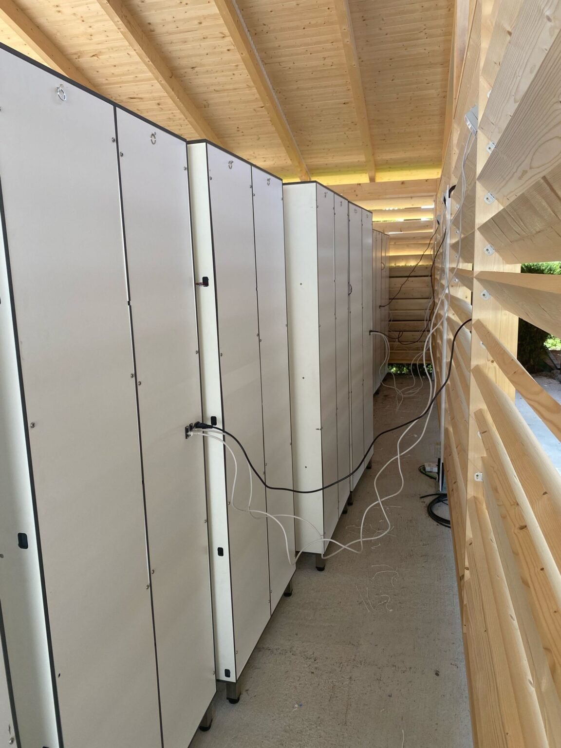 Installation de casiers connectés dans un établissement scolaire, optimisant l'espace avec des armoires blanches sous un plafond en bois